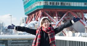 雪景色の東京タワーで手を広げて立つ女性